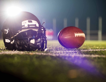 a football and a helmet sitting in the field