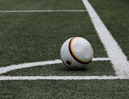 soccer ball sitting in the corner of a soccer field