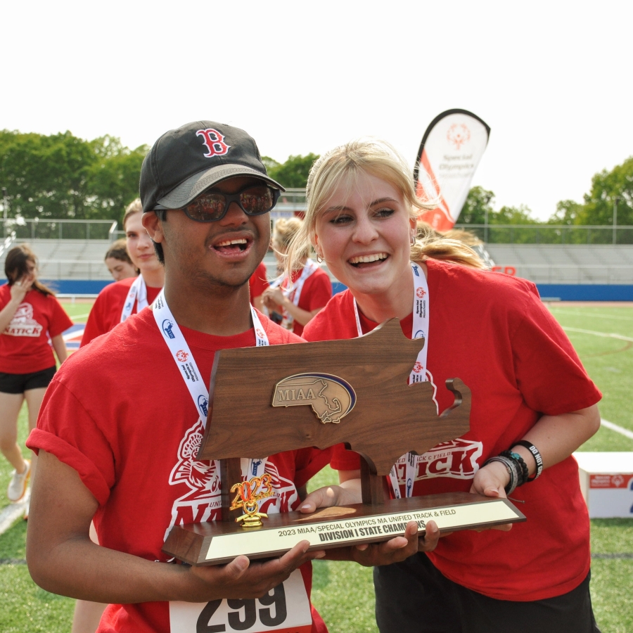 Players in red shirts pose while holding a trophy